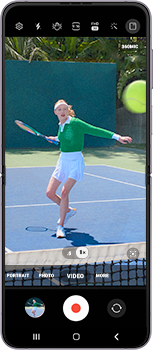 The Camera app is open and in video recording mode. A woman is playing tennis in the view finder.