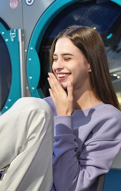 A woman laughing in a laundromat, taken in Portrait Mode with Studio effect applied.