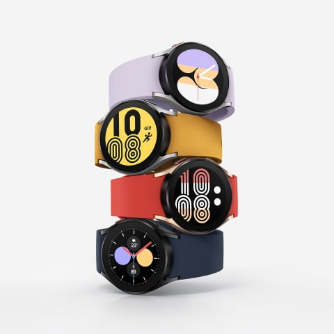 Four Galaxy Watch4 devices are stacked on top of each other with each watch showing a different watch face to tell the time. Each watch has a different color watch band, from Violet to Mustard to Red to Navy.