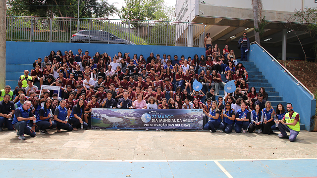 Students in uniform and Samsung Electronics employees and pose for a group photo holding a banner that reads “Preserve Glaciers,” after participating in a water replenishment awareness program in celebration of World Water Day.