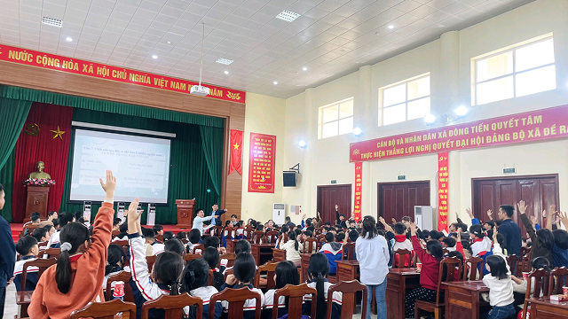 Students raise their hands to answer questions during a quiz session about a water replenishment program, held in an auditorium.