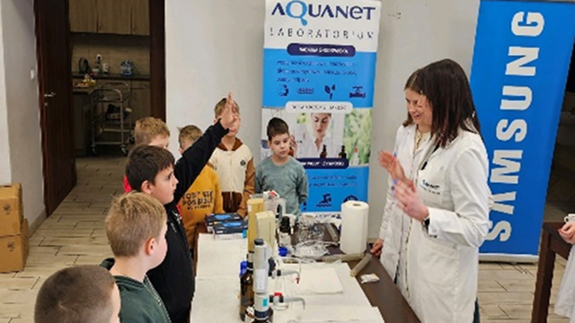As part of a water replenishment program, researchers lead a hands-on water quality education session with children, one of whom is raising a hand to ask a question.
