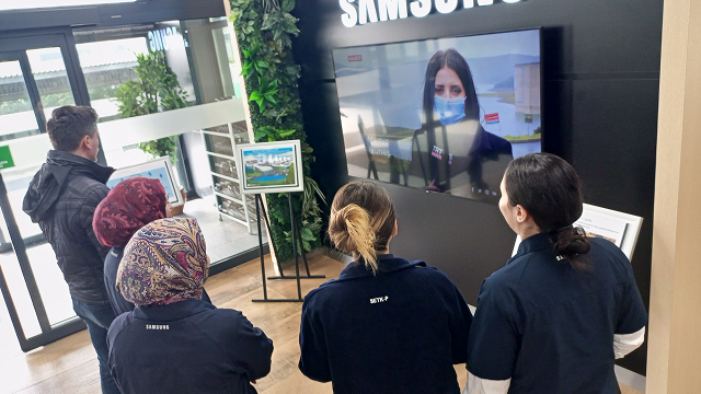 Samsung Electronics employees watch a water-saving campaign video displayed on a screen inside the company building.