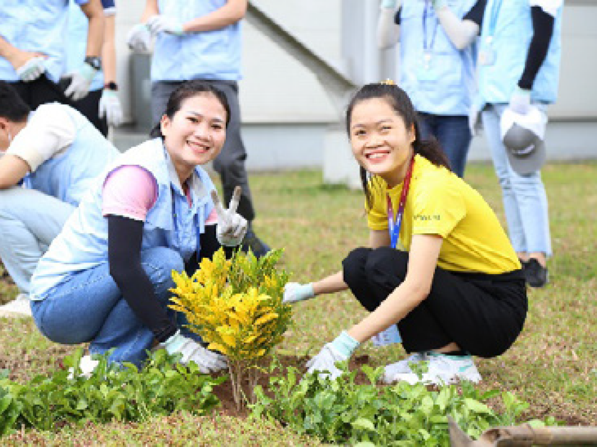인근 유역 정화 활동에 참여 중인 두 여성이 나무를 심으면서 카메라를 보고 활짝 웃는 모습