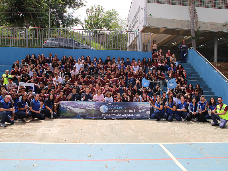 Students in uniform and Samsung Electronics employees and pose for a group photo holding a banner that reads “Preserve Glaciers,” after participating in a water replenishment awareness program in celebration of World Water Day.