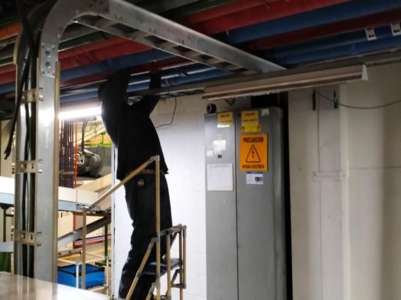 As part of a water-saving campaign, a technician inspects and repairs an overhead piping system inside an industrial facility.