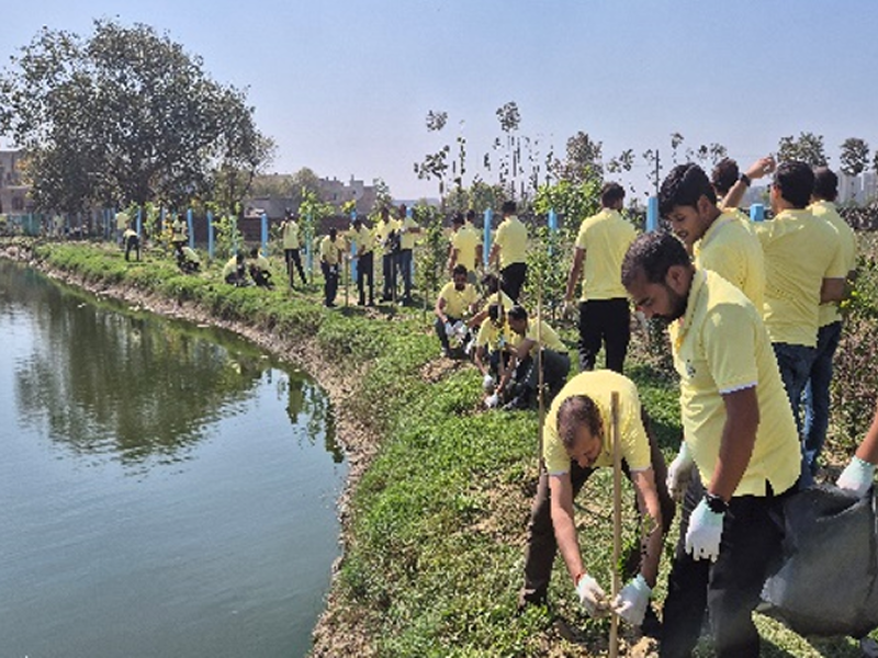 SSamsung Electronics employees in yellow shirts plant trees along a stream near the business site as part of an aquatic ecosystem protection activity.